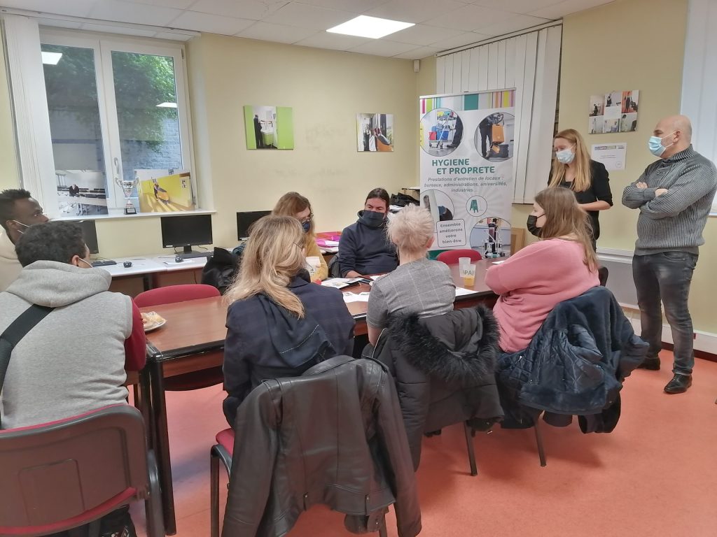 Une dizaine de personnes masquées échangent autour de tables, devant un kakémono « Hygiène et propreté ».