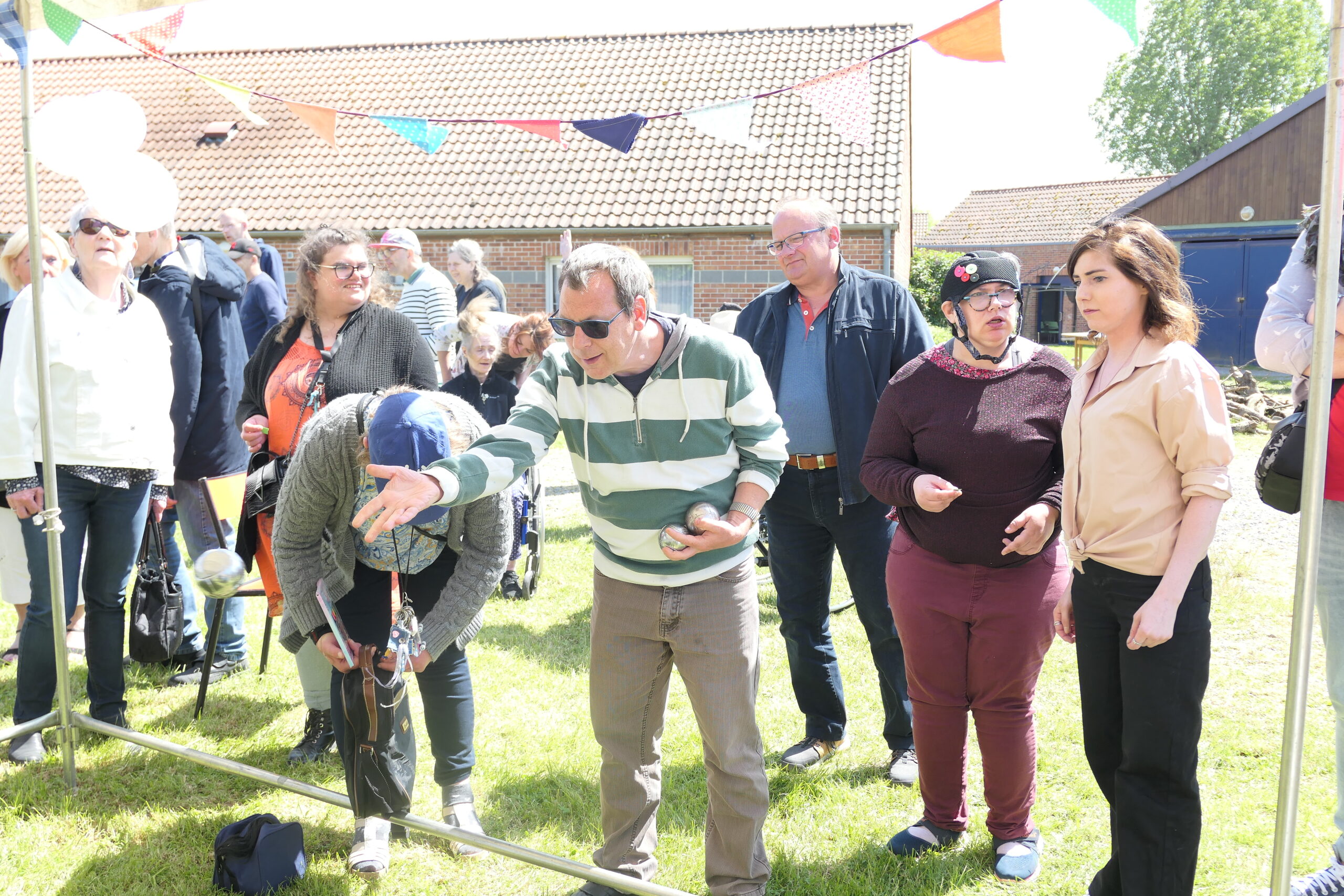 Un homme s’apprête à lancer une boule devant les spectateurs, sous les guirlandes de fanions