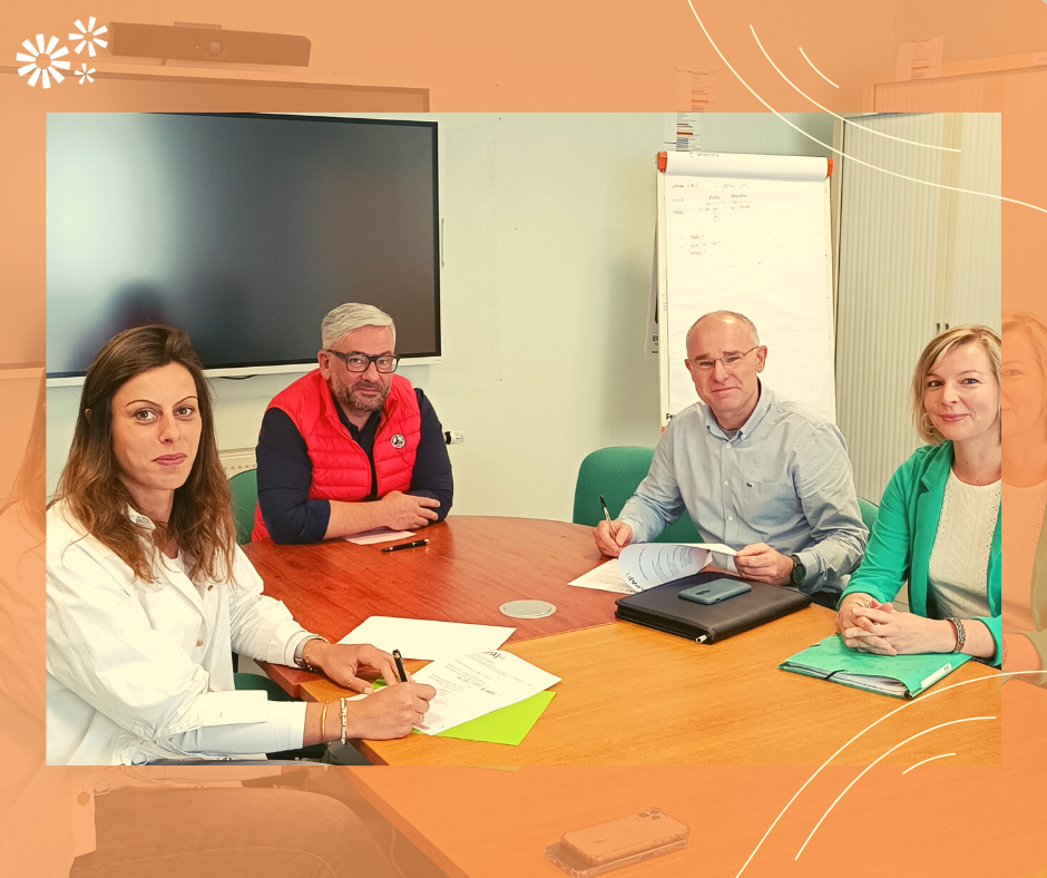 Quatre personnes réunies autour d'une table signent des documents, dans un cadre orange APAJH
