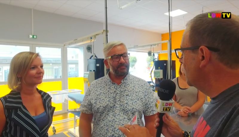 Un homme répond au micro d'une web TV dans une salle de rééducation, une femme à ses côtés