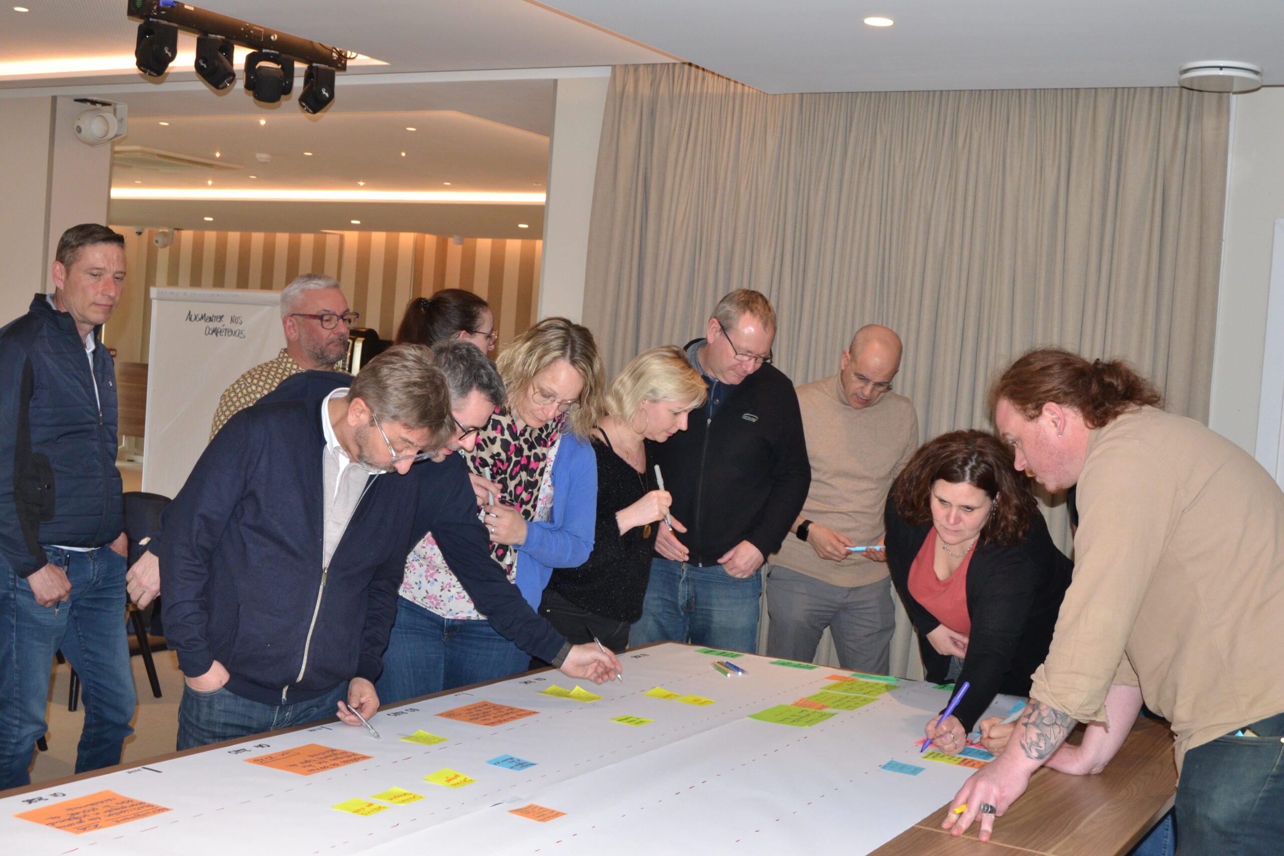 Autour d'une grande frise de papier couverte de post-it, des participants notent leurs idées lors d'un atelier.