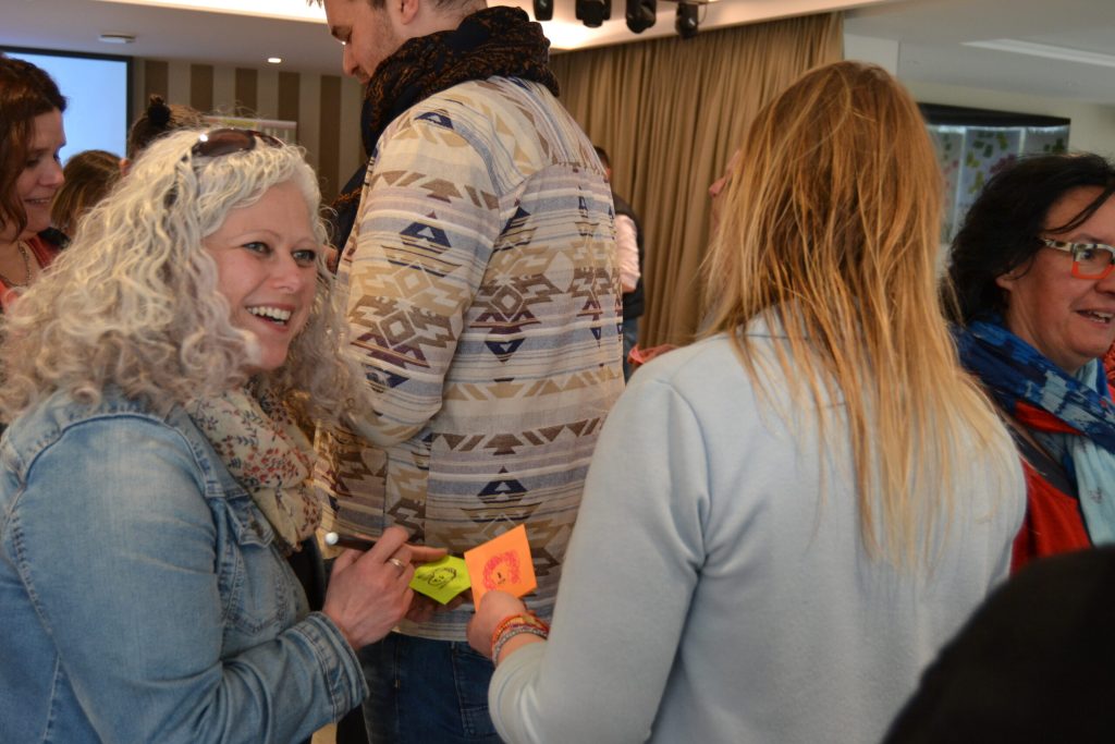 Lors d'un atelier participatif, des adultes échangent debout, des post-it colorés à la main.