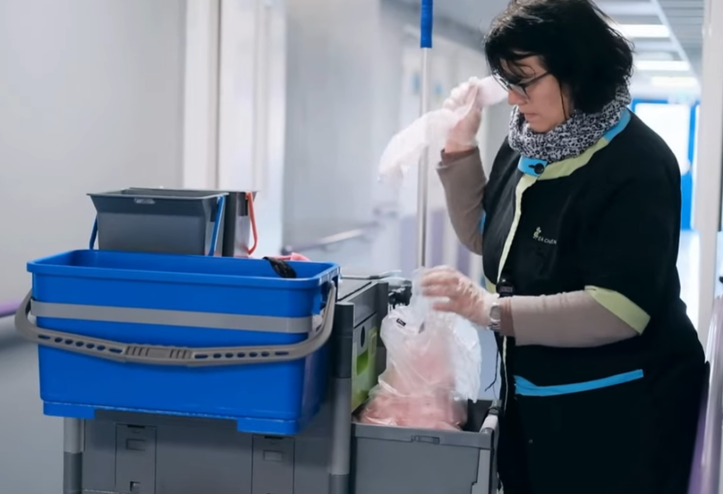 Agente de Challenge préparant son chariot de nettoyage dans un couloir