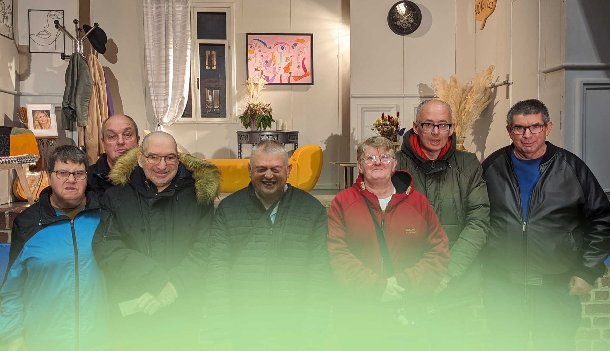 Sept adultes en manteau posent côte à côte dans un salon d'accueil orné d'un tableau coloré.